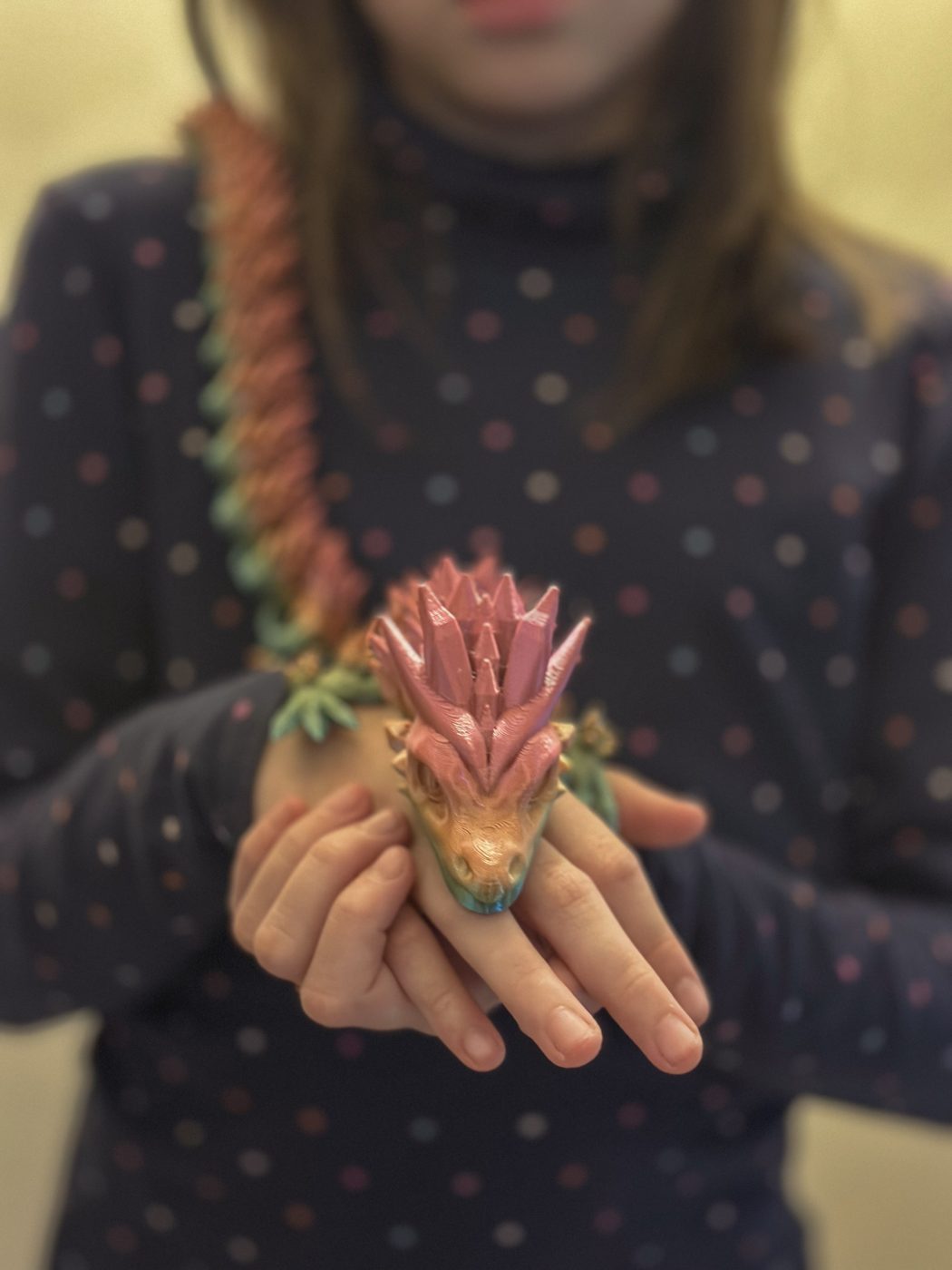 Dragón articulado impreso en 3D sostenido en las manos